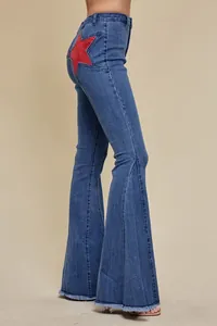 Side view of high-waisted flared jeans featuring a red star patchwork and frayed hem.