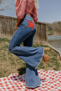 Stylish women's flare denim jeans featuring a bold red star patch and trendy raw hem finish