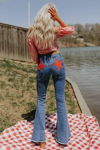 Back view of women's blue flare jeans featuring vibrant red star patch details.