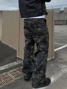 Detailed view of men's loose camouflage cargo pants with side pockets in outdoor setting