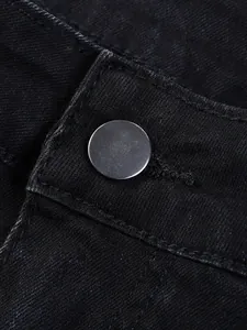 Detailed macro view of silver metallic waist button and premium black denim fabric on men's jeans