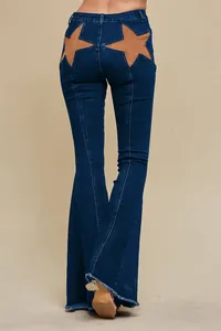 Back view of flared denim jeans featuring large tan star patchwork designs and frayed hems.