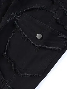 Close-up detail of black distressed denim pocket with fringe accents and metal button