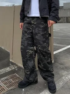 Detail view of men's dark camouflage cargo pants with a loose fit and streetwear style