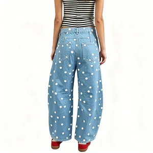 Rear view of women's loose light blue denim pants with white polka dot pattern detail