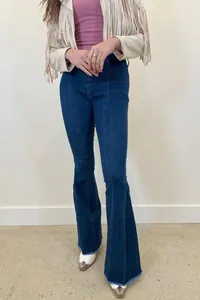 Close-up of women's dark blue flare jeans featuring vertical seams and raw hems