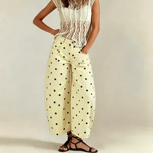 Detailed view of women's yellow polka dot wide-leg barrel jeans and lace top ensemble.