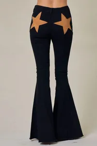 Detail view of black flared jeans featuring large tan star-shaped back pocket patches.