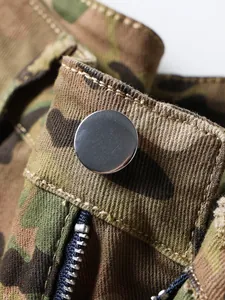 Macro view of silver metal button and zipper detail on men's camouflage cargo pants