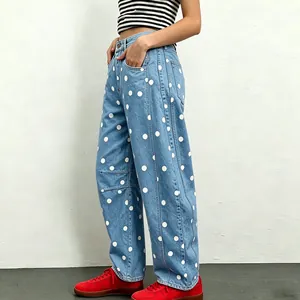 Detail view of light blue low-waist loose jeans with large white polka dot pattern