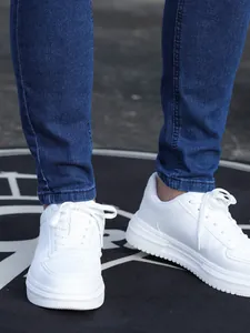 Dettaglio di jeans skinny elasticizzati blu da uomo abbinati a sneakers bianche trendy