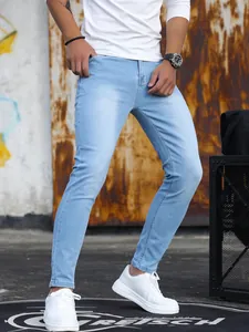 Dettaglio di jeans skinny elasticizzati da uomo in lavaggio azzurro con scarpe bianche.