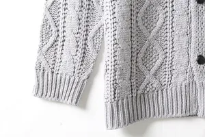 Dettaglio macro del cardigan grigio a trecce da uomo con polsino e orlo a costine