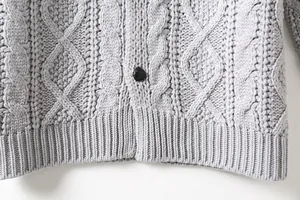 Dettaglio macro del cardigan da uomo grigio a trecce con bottone e bordo a costine