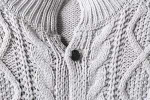 Dettaglio macro della trama in maglia a trecce grigia e bottone su cardigan da uomo