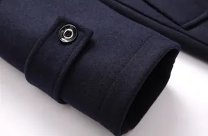 Detalle del puño de un abrigo de lana azul marino con una correa decorativa con botones