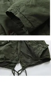 Detail view of a green men's jacket featuring zipper, snap buttons, and drawstring hem.