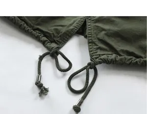 Macro detail of men's jacket drawstring with silver metal tips on green cotton fabric