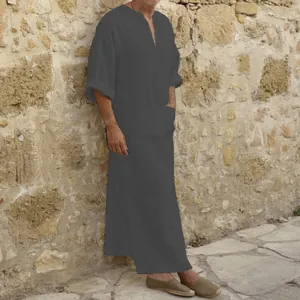 Detailed view of men's long cotton linen robe in dark grey against stone wall