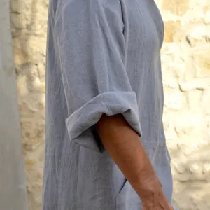 Detail of rolled-up sleeve on men's dusty blue cotton linen robe with natural texture