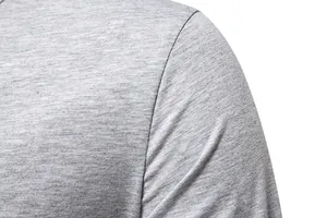 Close-up of grey heather fabric on a men's long sleeve Henley T-shirt shoulder.
