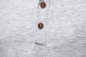 Detailed macro shot showing the brown buttons and fabric texture of a grey Henley T-shirt