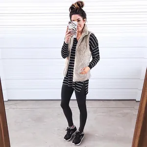 Detailed look at a fuzzy women's plush zip-up vest layered over a striped long sleeve tunic