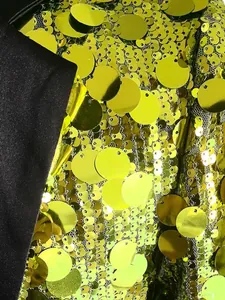 Dettaglio ravvicinato delle grandi paillettes verde lime e del revers in raso nero su un blazer