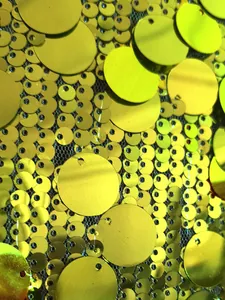 Dettaglio macro di paillettes gialle vivaci su tessuto mesh per abito da uomo moda