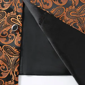Close-up of men's orange paisley jacquard suit vest showing black satin lining and button.