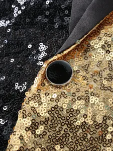 Close-up detail showing the intricate black and gold sequins and button of a suit jacket.