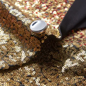 Detail van glanzende goud en rode lovertjes op een heren colbert voor het podium met zilveren knoop