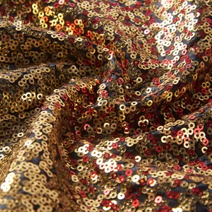 Macro-opname van glinsterende gouden en rode pailletten op een podium blazer stof