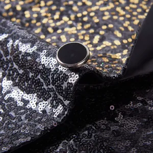 Detailopname van een pailletten blazer met zwart knoopje en glinsterende textuur nu.