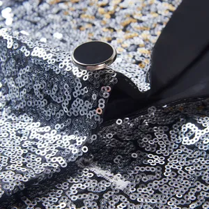 Close-up van zilveren lovertjes en zwarte knoop op een heren blazer voor op het podium.