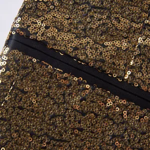 Gedetailleerd macrobeeld van fonkelende gouden lovertjes op de zwarte stof van een blazer