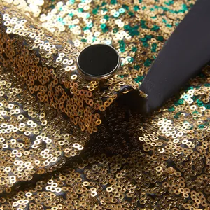 Detailopname van goud en groene gradiënt lovertjes op een heren blazer met zwarte knoop