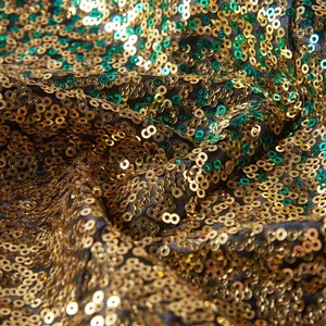 Detailopname van luxe gouden en groene pailletten op een zwarte podium blazer stof