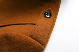 Nahaufnahme des hochwertigen braunen Wollstoffs und des schwarzen Knopfes an einem Herrenmantel
