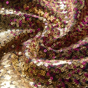 Macrodetail van gradiënt paillettenstof met goudkleurige en fuchsia fonkelingen.