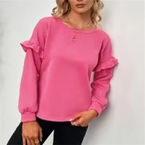 Dettaglio di una felpa rosa a maniche lunghe con balze indossata da una modella bionda.