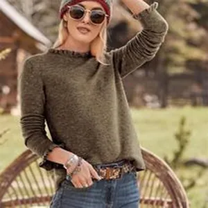 Dettaglio di un maglione a maniche lunghe verde oliva con delicati volant su polsini e colletto.