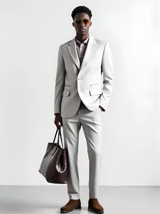 Detail shot of a male model posing in a silver slim-fit business suit and brown bag.