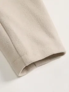 Detail shot of men's beige wool coat sleeve cuff showing fine fabric texture detail