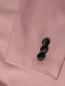 Detailed macro view of a pink business suit sleeve featuring black satin-covered buttons