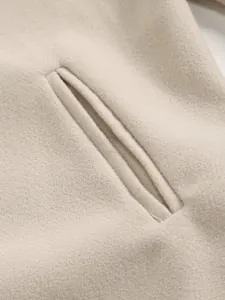 Close-up detail of a cream-colored men's woolen coat showing high-quality welt pocket