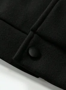 Close-up macro shot of a matte black button on a premium black woolen jacket fabric