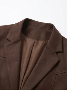 Détail d'un blazer en daim marron avec revers cranté et doublure intérieure douce.