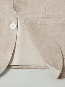Close-up detail of beige textured men's business suit jacket with white button