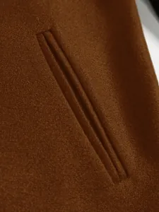 Close-up of pocket detail on a high-quality brown men's wool coat with premium texture.